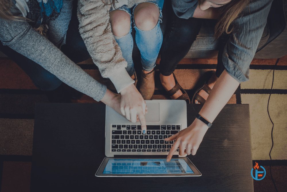 Three women reading about must-try marketing trends for 2022 on a laptop.