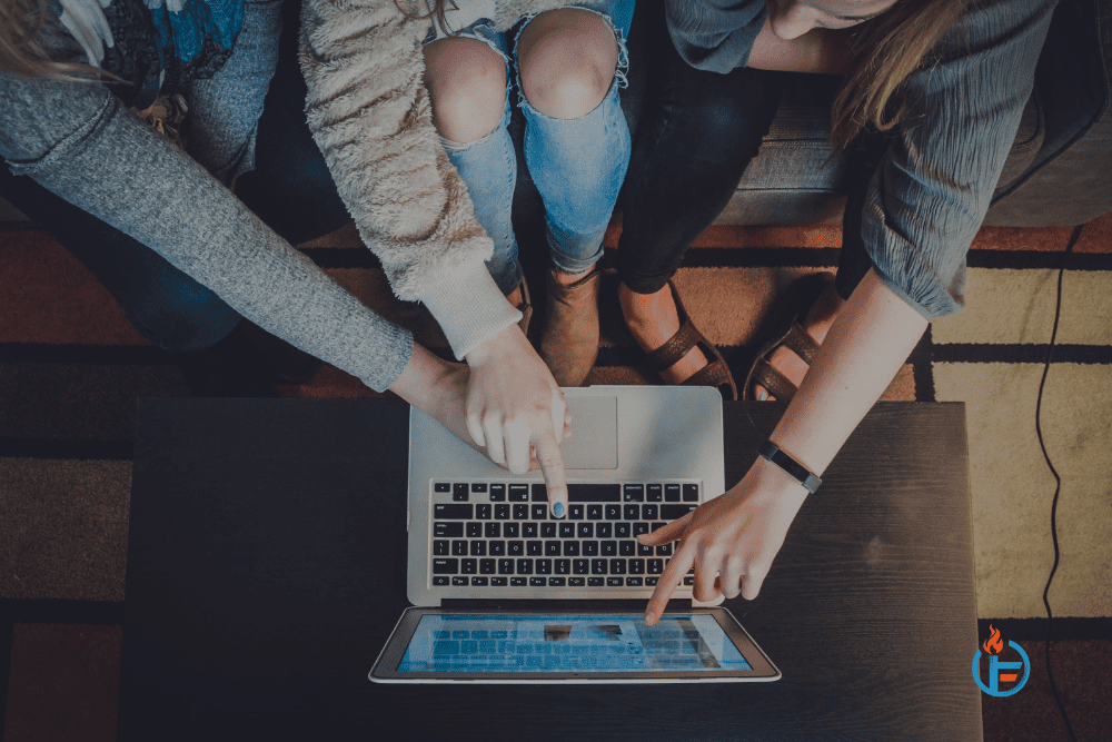 Three women reading about must-try marketing trends for 2022 on a laptop.
