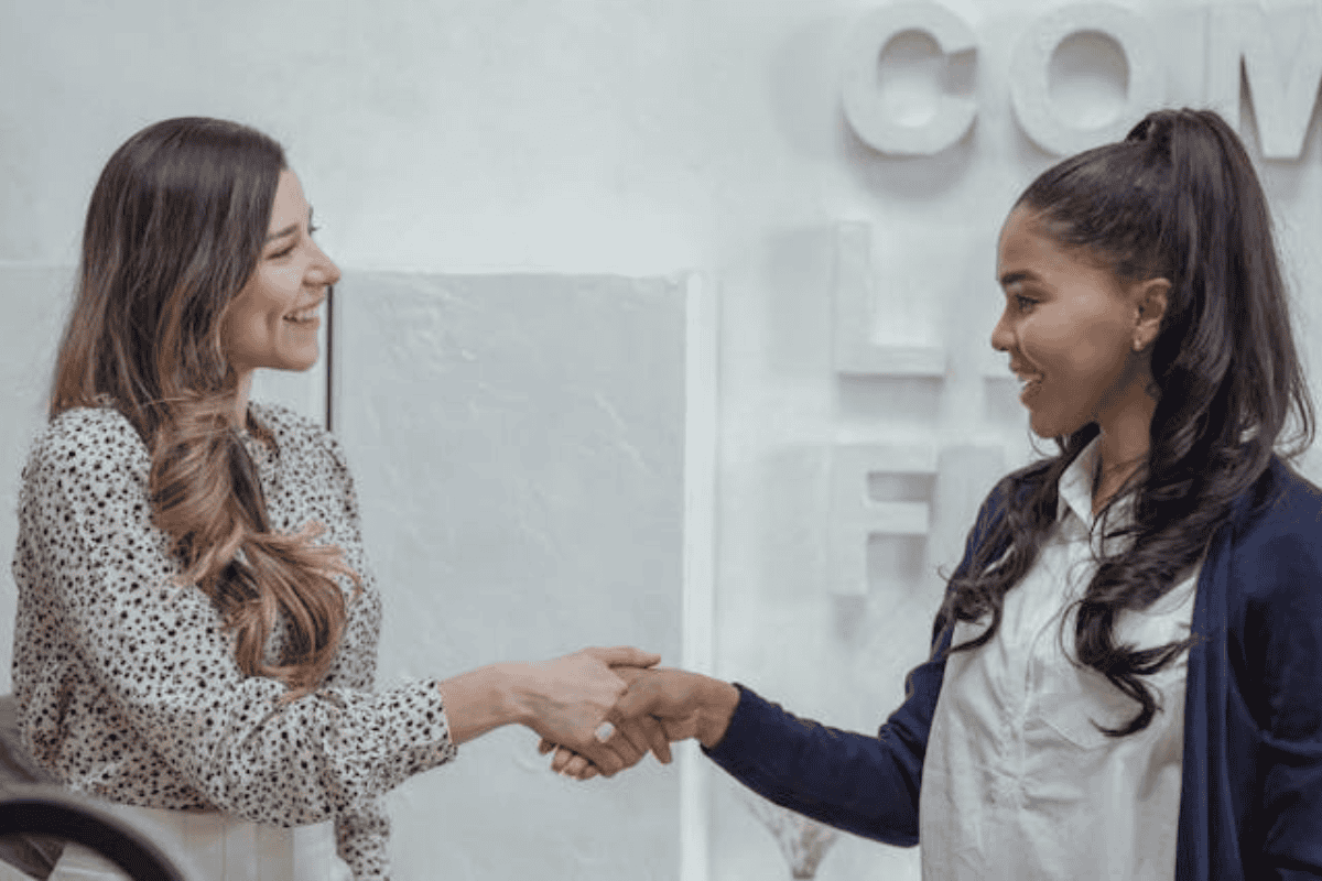Two women shaking hands and smiling